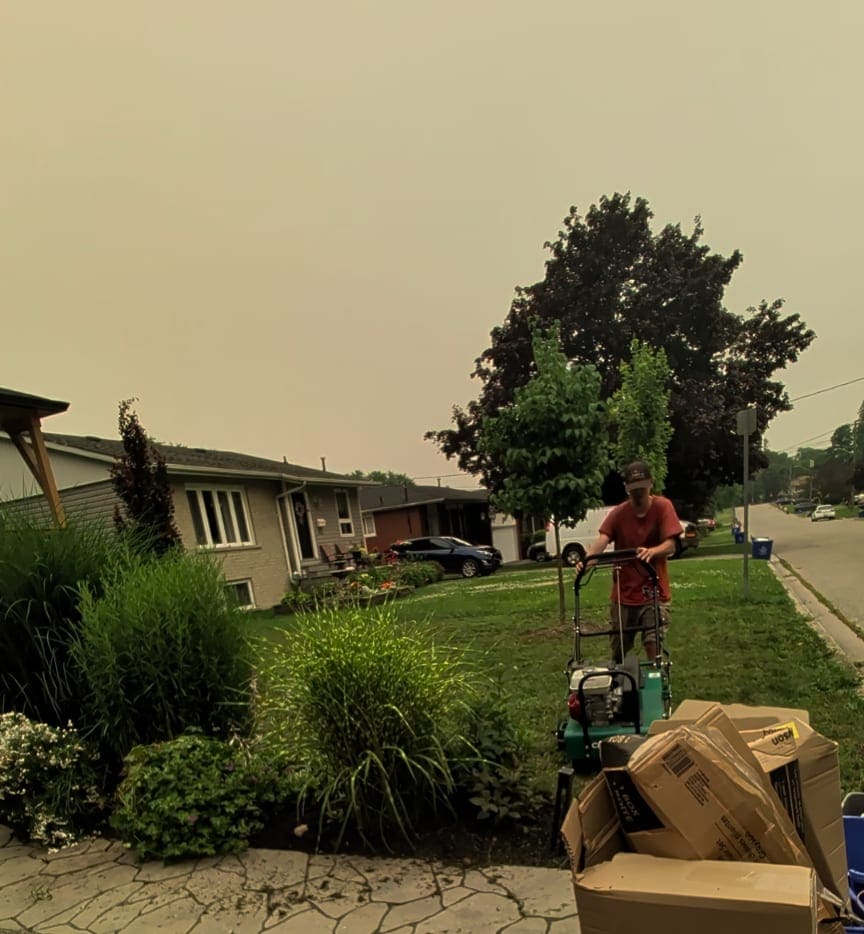 Crew member operating a core aerator on a front lawn in a residential neighbourhood